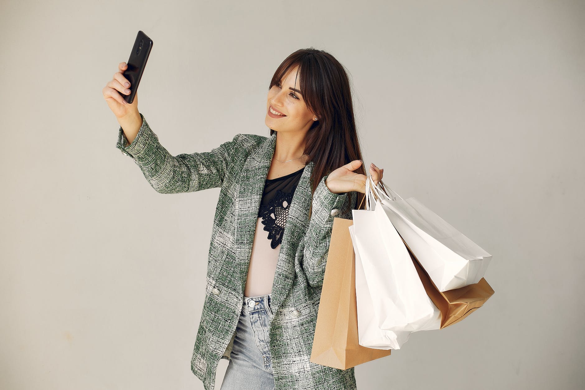 happy young woman with shopping bags taking selfie