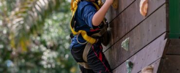 a boy with blue helmet climbing on a wooden wall