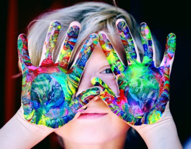 a kid with multicolored hand paint