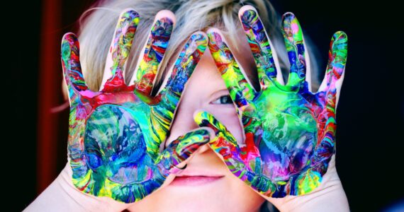 a kid with multicolored hand paint