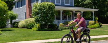 a man riding a bike on a street in front of a house