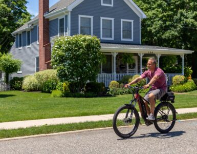 a man riding a bike on a street in front of a house