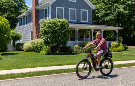 a man riding a bike on a street in front of a house