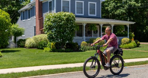 a man riding a bike on a street in front of a house