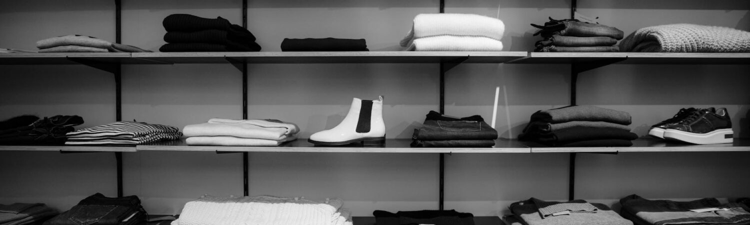 grayscale photography of assorted apparels on shelf rack