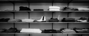 grayscale photography of assorted apparels on shelf rack