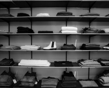 grayscale photography of assorted apparels on shelf rack