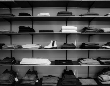 grayscale photography of assorted apparels on shelf rack