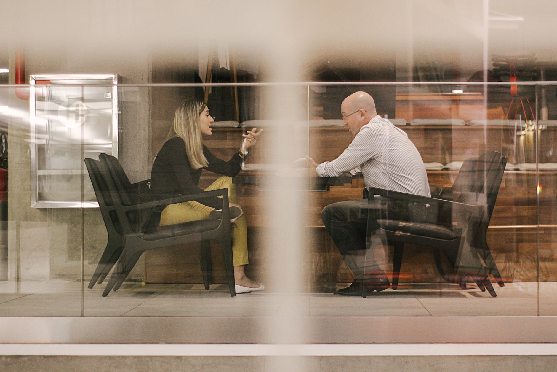 man and woman sitting on black wooden chairs