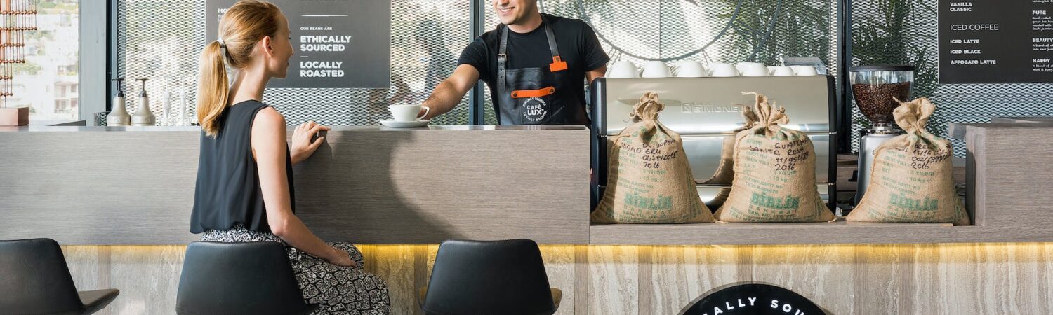 woman sitting on bar chair near barista