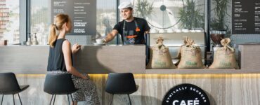 woman sitting on bar chair near barista