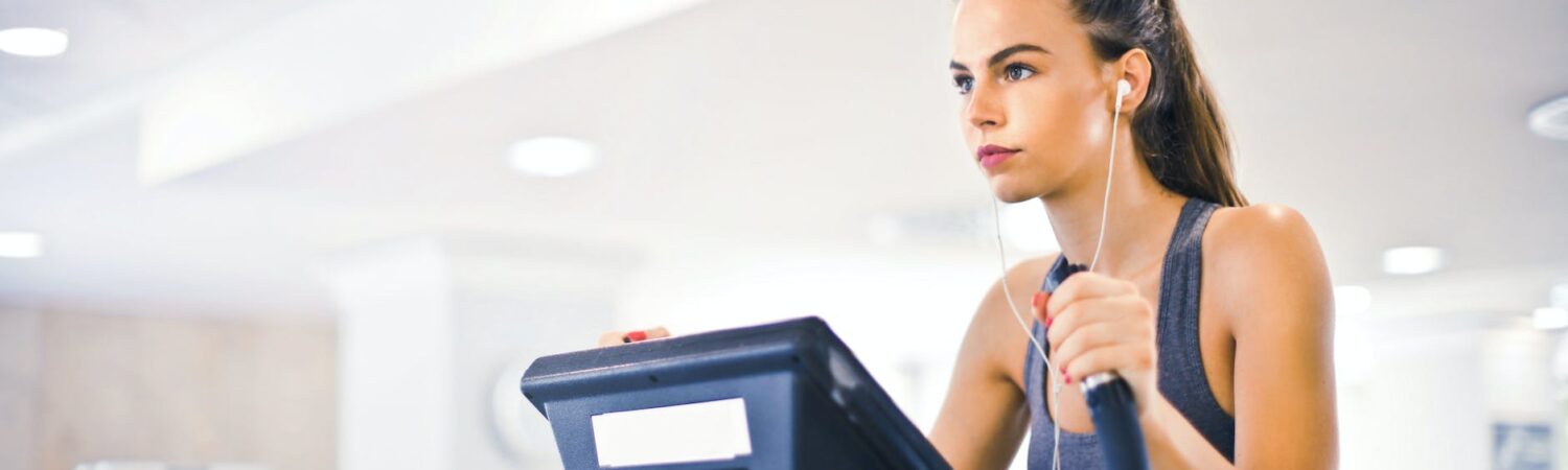 young female athlete training alone on treadmill in modern gym