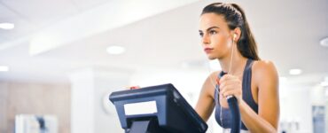 young female athlete training alone on treadmill in modern gym