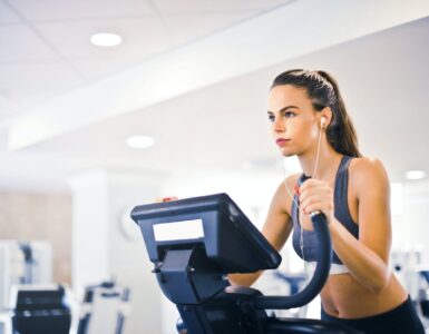 young female athlete training alone on treadmill in modern gym