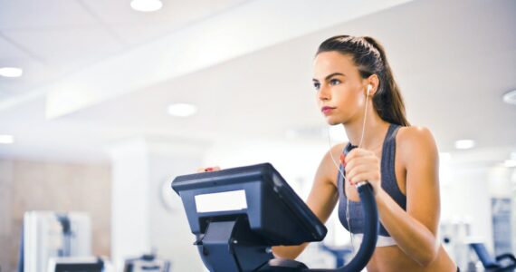 young female athlete training alone on treadmill in modern gym