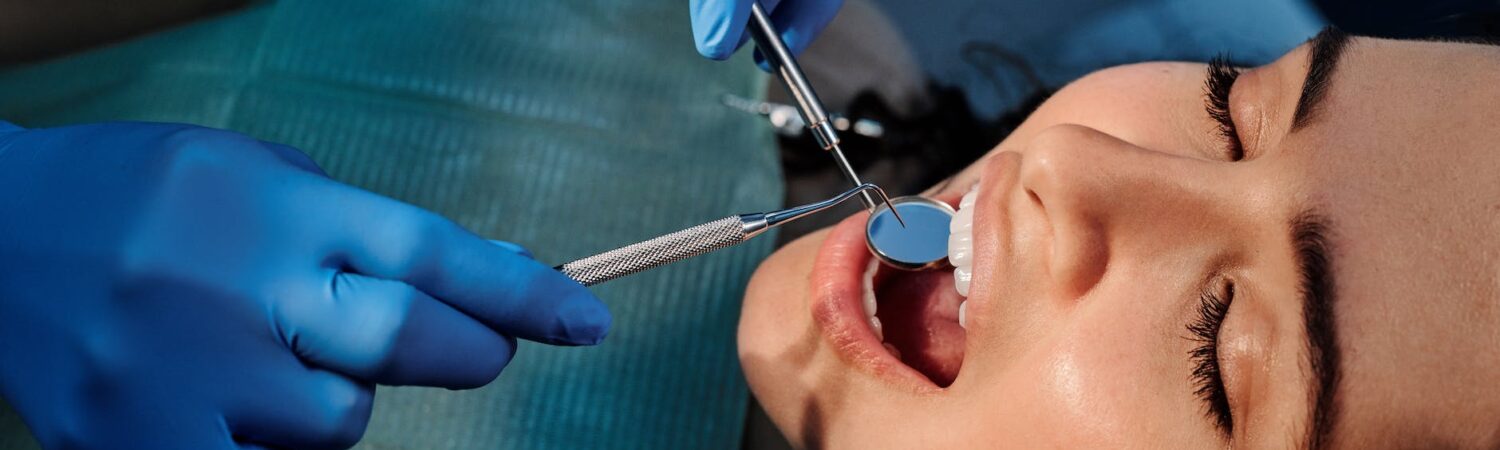 a person wearing blue latex gloves holding a mirror in a woman s mouth