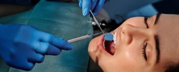 a person wearing blue latex gloves holding a mirror in a woman s mouth