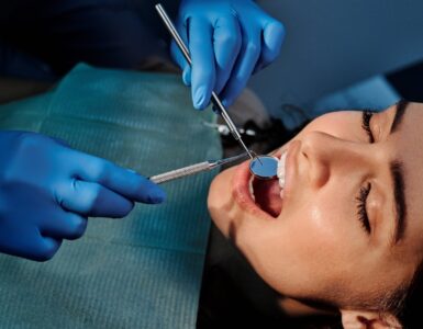 a person wearing blue latex gloves holding a mirror in a woman s mouth