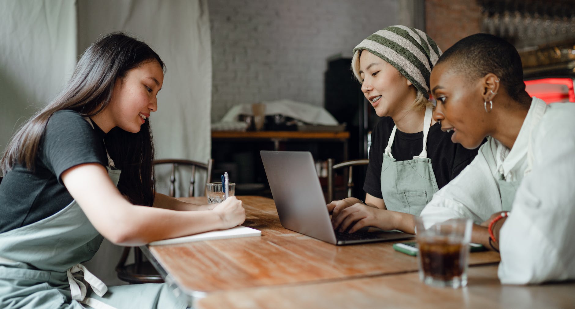 cheerful diverse colleagues working on laptop and taking notes