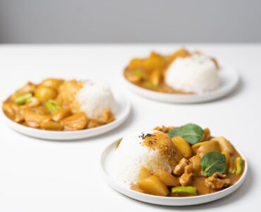 plates with tasty curry placed on white table