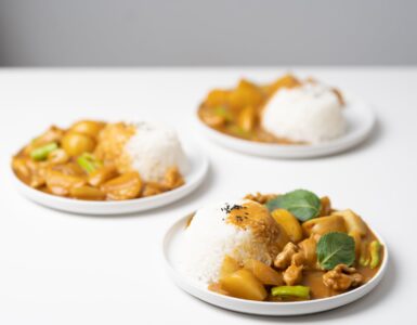 plates with tasty curry placed on white table