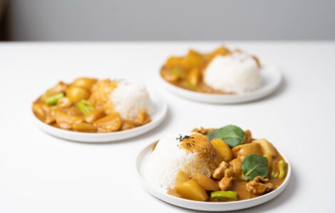 plates with tasty curry placed on white table