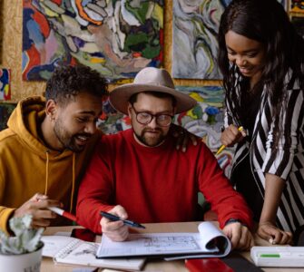 men and woman discussing project in a sketchbook and abstract paintings hanging on a wall