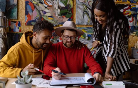 men and woman discussing project in a sketchbook and abstract paintings hanging on a wall