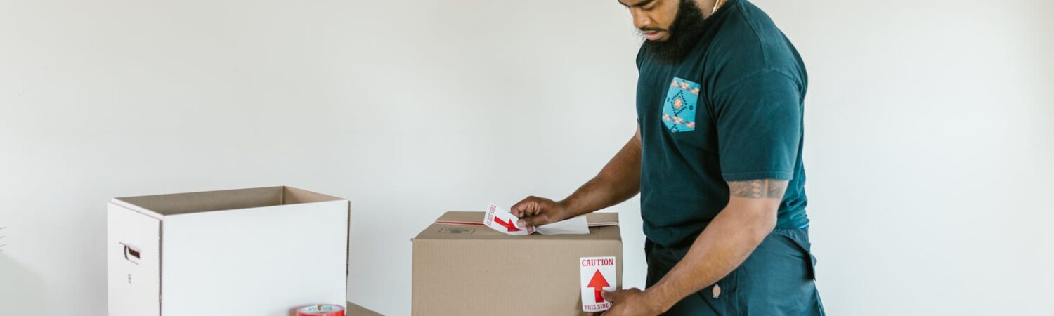 man putting caution stickers on cardboard boxes