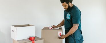 man putting caution stickers on cardboard boxes