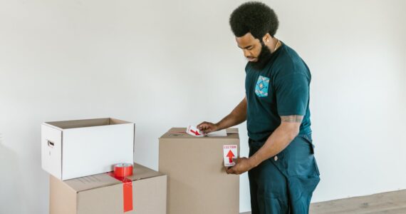 man putting caution stickers on cardboard boxes