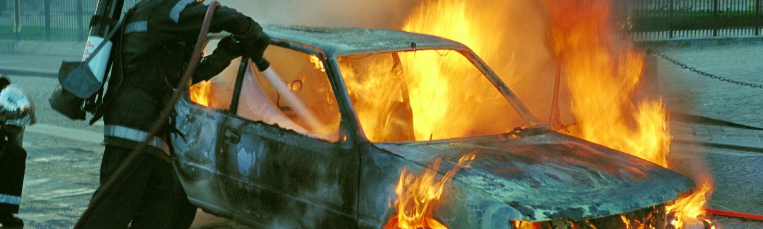 firefighter extinguishing a burning car