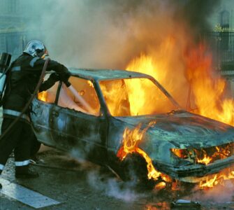 firefighter extinguishing a burning car