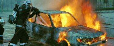 firefighter extinguishing a burning car