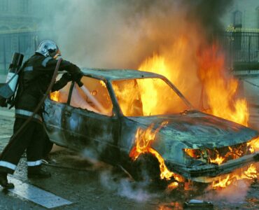 firefighter extinguishing a burning car