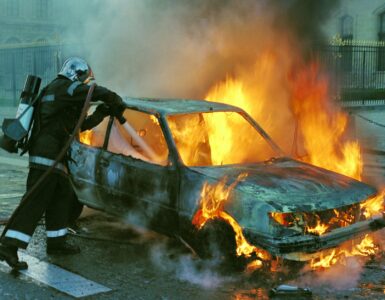 firefighter extinguishing a burning car