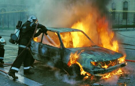 firefighter extinguishing a burning car