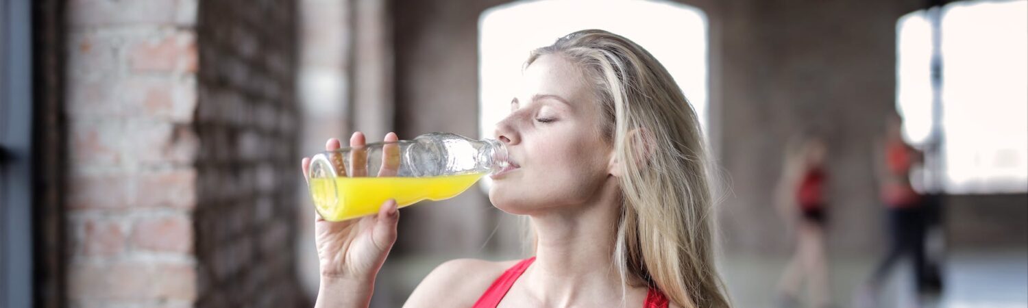 selective focus photography of woman in red tank top drinking