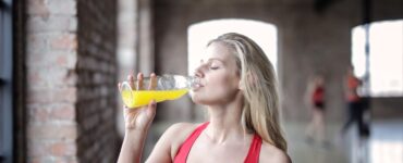 selective focus photography of woman in red tank top drinking