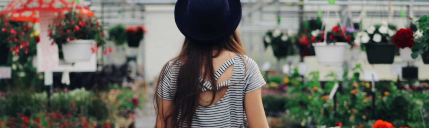 woman walking between display of flowers and plants