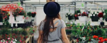 woman walking between display of flowers and plants