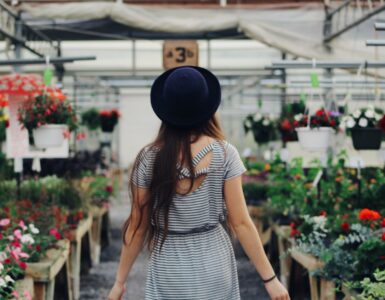 woman walking between display of flowers and plants