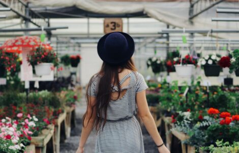 woman walking between display of flowers and plants