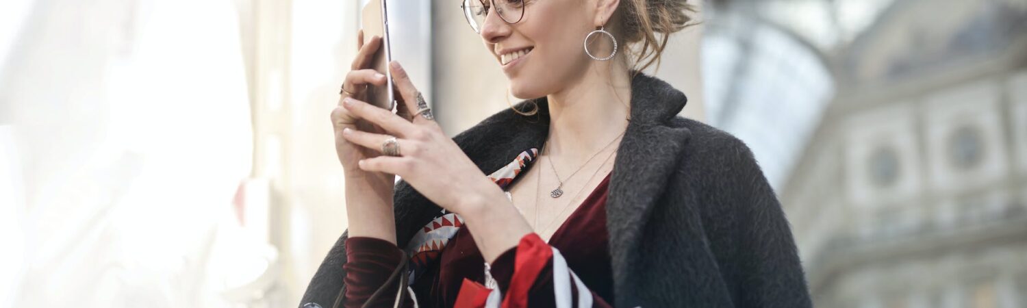 woman standing near wall holding phone