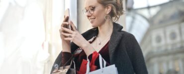 woman standing near wall holding phone