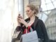 woman standing near wall holding phone